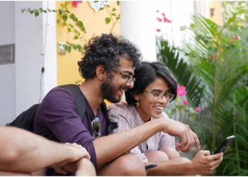 Two people smiling while using a phone